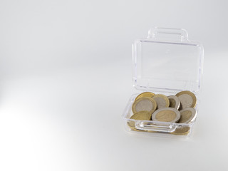 Small transparent suitcase full of euro coins isolated on white background