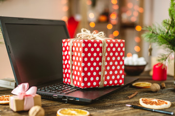 Gift red box with white polka dots on the laptop. Purchase discounts for Christmas and new year in online stores.