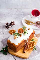 Fruit cake dusted with icing, nuts and dry orange on stone background. Christmas and Winter Holidays homemade cake