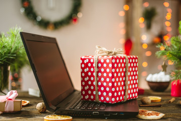 Naklejka na ściany i meble Gift red box with white polka dots on the laptop. Purchase discounts for Christmas and new year in online stores.