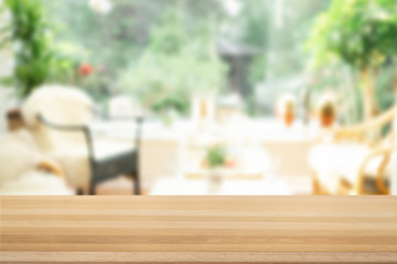 Brown empty wooden table top with blurred living room that can see garden background. Light wood...