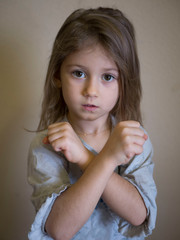 portrait of a disgruntled little blonde girl covering her arms, child protection concept