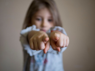 portrait of unhappy little girl the blonde points his index fingers at the camera, the concept of...