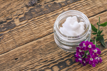 Cosmetic cream, fresh verbena flowers on wooden background.