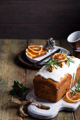 Fruit cake dusted with icing, nuts and dry orange on old wooden background. Christmas and Winter Holidays homemade cake