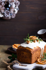 Fruit cake dusted with icing, nuts and dry orange on old wooden background. Christmas and Winter Holidays homemade cake
