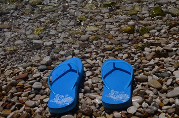 Niebieskie klapki na kamienistej plaży