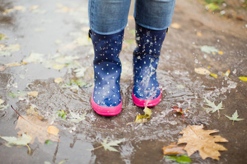 Woman in blue rubber boots jumping in puddle