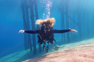 Woman scuba diver freely floating in the blue transparent water enjoing a fun.
