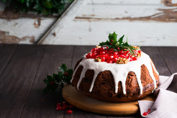 Christmas homebaked chocolate cake decorated with white icing and pomegranate kernels against the background of old wooden doors