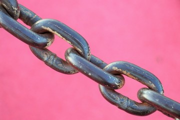 Close-up of several links of a metal chain on a red background