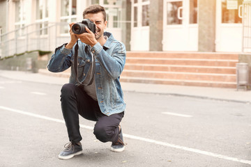 Young male photographer with camera outdoors