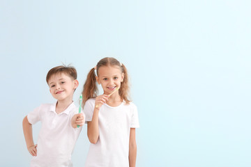 Portrait of little children brushing teeth on light background