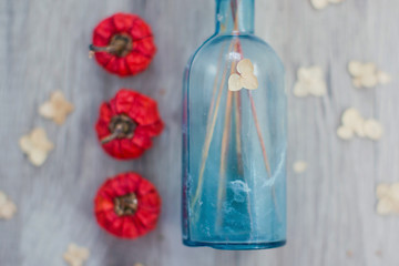 red dried grass in blue glass vase and small pumpkins