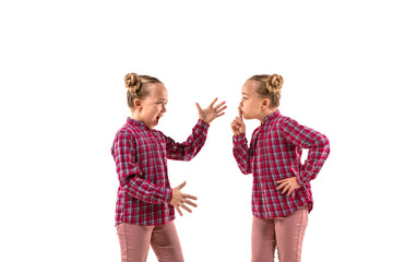 Young handsome girl arguing with herself on white studio background. Concept of human emotions, expression, mental issues, internal conflict, split personality. Half-length portrait. Negative space.