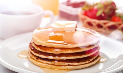 Stack of Small pancakes in syrup on background