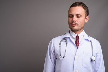 Portrait of handsome man doctor against gray background