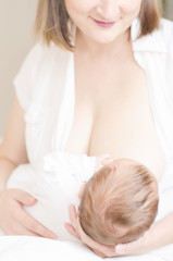 Obraz na płótnie Canvas Young happy smiling mom breastfeeding her little baby boy.