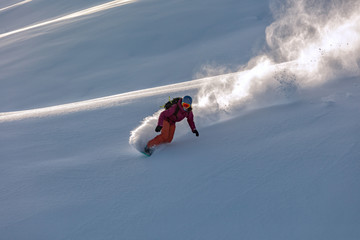 freerider in a bright suit rides fast skiing with large splashes of snow on a sunny day. Young...