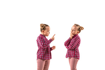 Young handsome girl arguing with herself on white studio background. Concept of human emotions, expression, mental issues, internal conflict, split personality. Half-length portrait. Negative space.