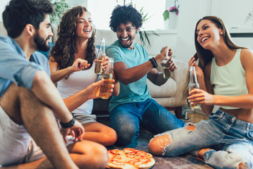 Group of multi ethnic young friends eating pizza at home and having fun.