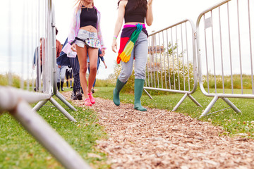 Close Up Of Friends At Entrance To Music Festival Walking Through Security Barriers