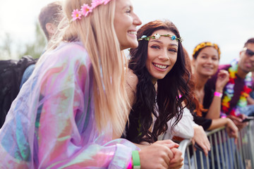 Group Of Young Friends Waiting Behind Barrier At Entrance To Music Festival Site