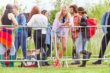 Group Of Young Friends Waiting Behind Barrier At Entrance To Music Festival Site