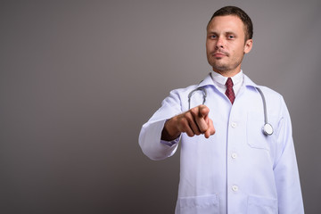 Portrait of handsome man doctor against gray background