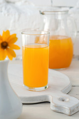 Apricot juice in glass and vase with flower
