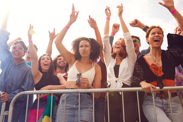 Cheering Young Friends In Audience Behind Barrier At Outdoor Festival Enjoying Music