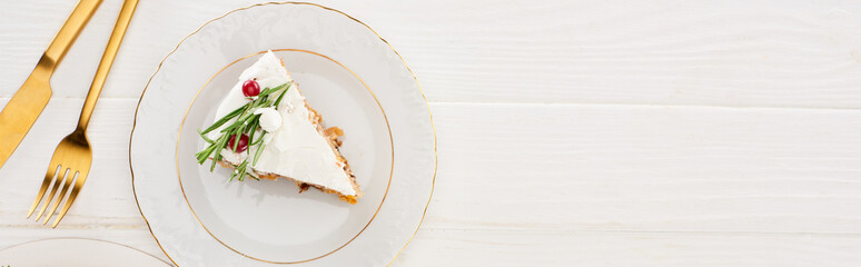 top view of christmas pie piece with fork and knife on white wooden table