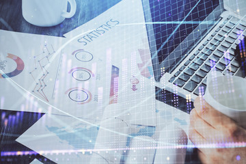 Double exposure of stock graph with businessman typing on computer in office on background. Concept of hard work.