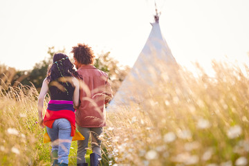 Young Romantic Couple Walking Through Field Towards Teepee On Summer Camping Vacation © Monkey Business
