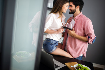 Image of happy couple with glasses of red wine eating salad