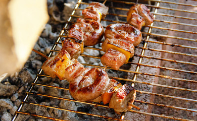 Meat and sausages skewers cooking on a grill