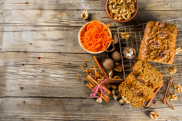 Homemade carrot cake with walnuts, rustic wooden background with ingredients, copy space