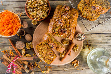 Homemade carrot cake with walnuts, rustic wooden background with ingredients, copy space