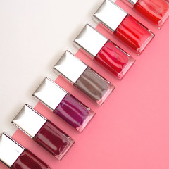 nail polishes of different colors are built on pink and white background concept flat lay