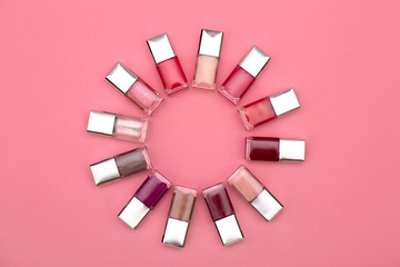 nail polishes of different colors are built on a pink background concept flat lay