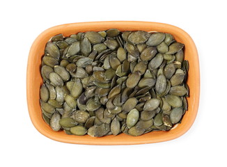 Pumpkin seeds in clay bowl isolated on white background, top view