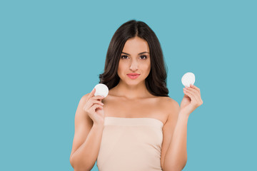 attractive woman holding cotton pads isolated on blue