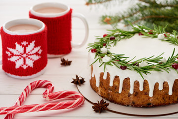 candy canes, christmas pie with icing and two cups of coffee on white wooden table