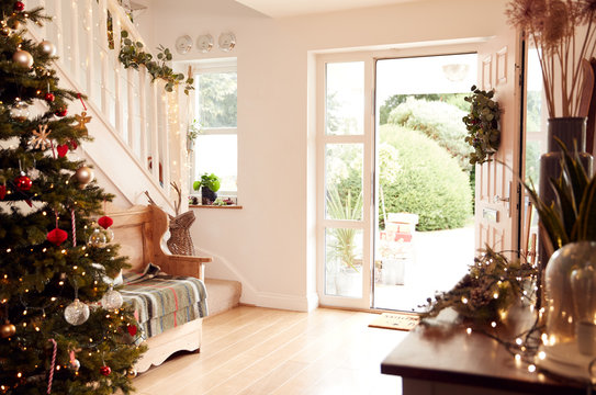 Hallway Of Home Decorated For Christmas Viewed Towards Open Front Door