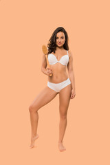 Obraz premium beautiful young woman holding body brush isolated on beige