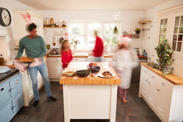 Motion Blur Shot Of Family In Kitchen Helping To Prepare Christmas Meal Together