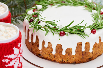 close up of christmas pie with icing on white wooden table with cups of cocoa