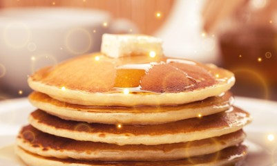 Panckes with butter and syrup with coffee in the background