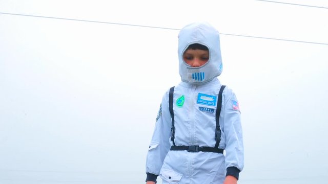 A boy in an astronaut costume is looking for a space station on the planet