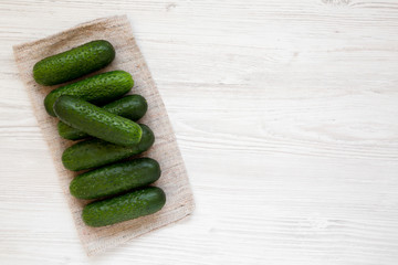 Fresh organic mini baby cucumbers on a white wooden background, top view. Flat lay, overhead, from above. Copy space.